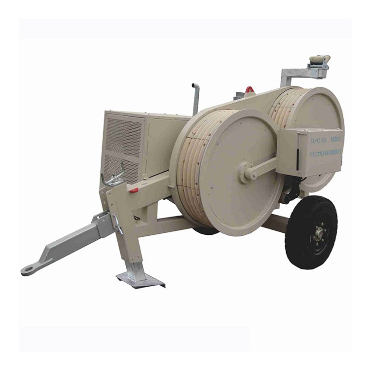 Heavy-duty hydraulic cable pulling winch with dual spools, engine, and trailer wheel for power line construction tasks.